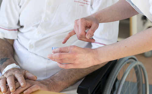 Patient i kørestol får medicin af sygeplejerske